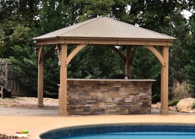 outdoor stone counter with wood pergola and pool